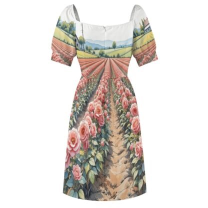 Soft floral dress with short sleeves, fitted bodice, open squarish neckline, gathered skirt, back zipper knee-length dress with an all-over print of pinkish roses with green foliage growing in rows towards the horizon with brown earth between the rows of roses and green farms beyond.